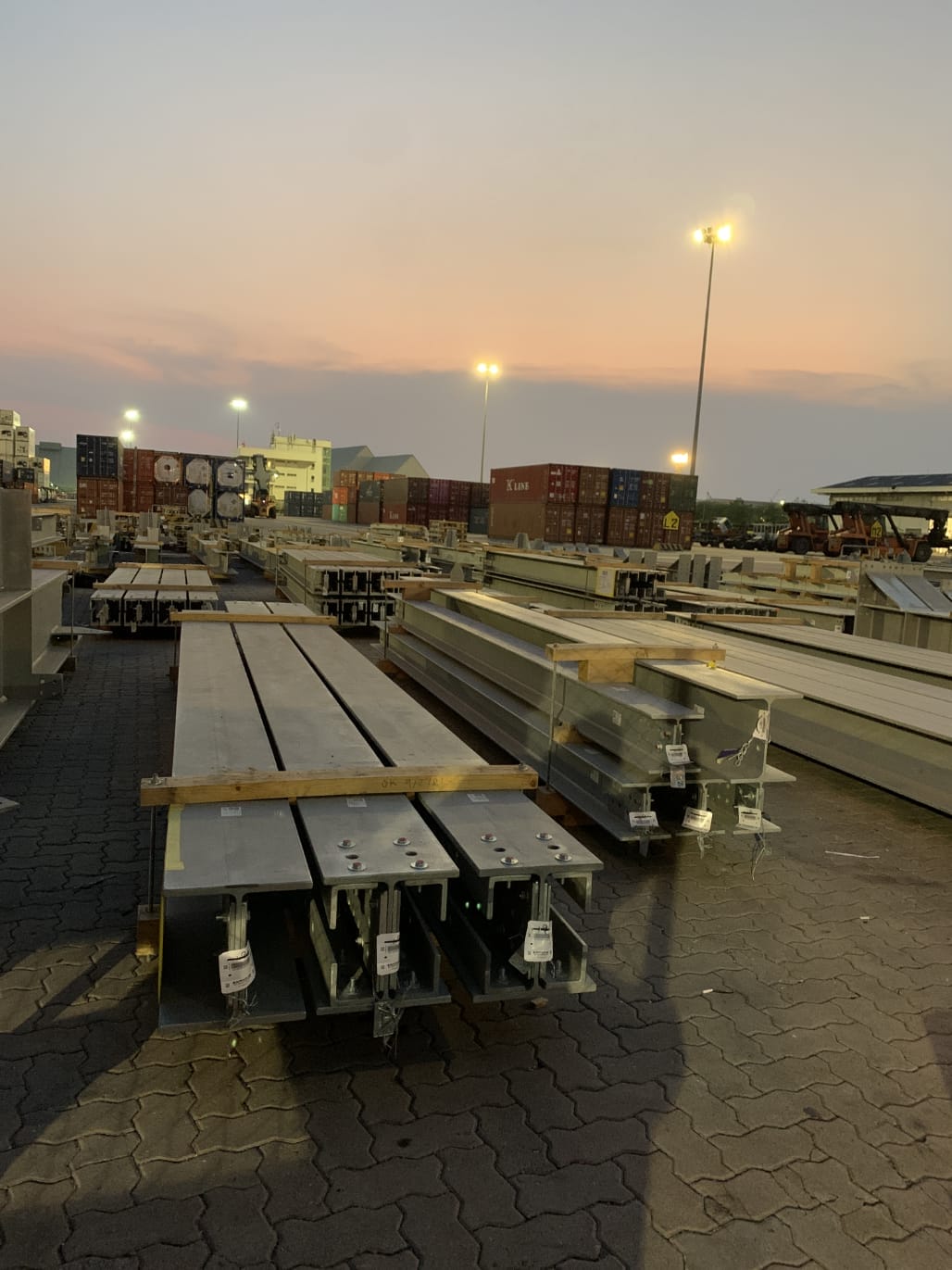 เหล็กโครงประกอบเรียงในลานส่งของ | Steel beams stacked in shipping yard